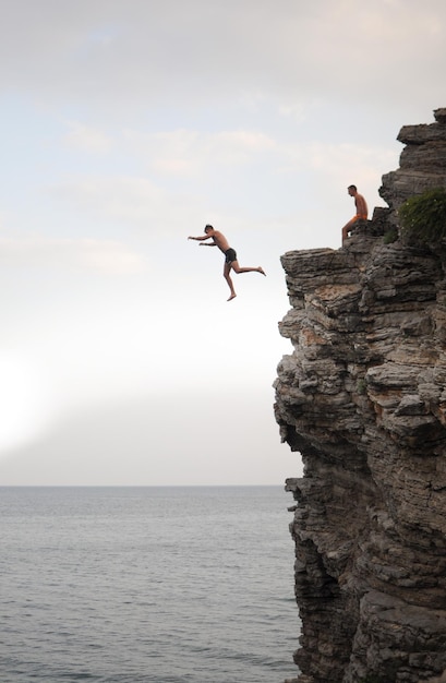 Ein Mann springt von einer hohen Klippe ins Meer