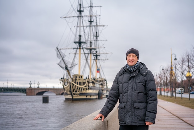 Ein Mann steht am Wasser vor dem Schiff auf der Newa