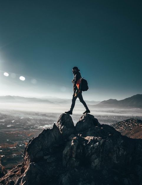 Ein Mann steht auf einem felsigen Berg gegen den Himmel