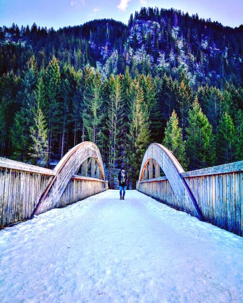 Foto ein mann steht auf einer schneebedeckten brücke