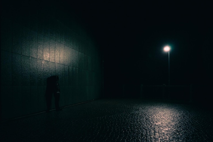 Foto ein mann steht in der nacht allein neben einer mauer