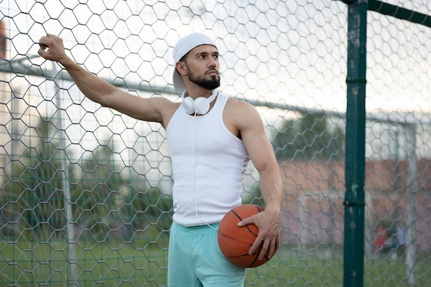 Ein Mann steht in der Nähe eines Zauns auf der Straße und hält einen Basketball in der Hand