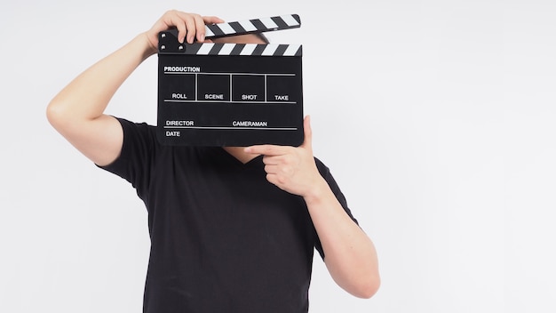 Ein Mann steht mit Händen und hält schwarzes Clapperboard oder Filmschiefer. es verwendet in der Videoproduktion, im Film, in der Kinoindustrie. Es ist weißer Hintergrund.