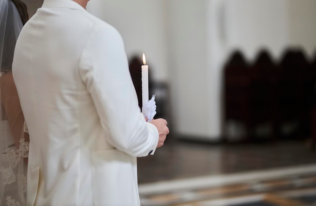 Ein Mann steht mit Kerzen in der Hand bei einer kirchlichen Trauung