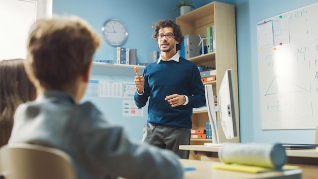 Ein Mann steht vor einem Computerbildschirm und spricht mit einem Mann in einem blauen Pullover.