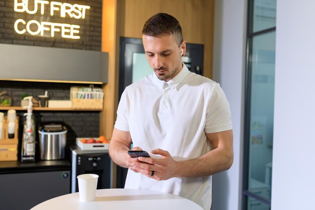 Ein Mann surft während einer Kaffeepause mit seinem Handy im Internet