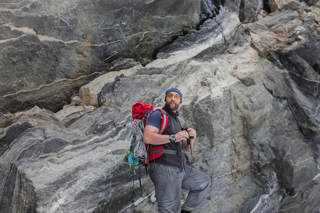 Ein Mann Tourist mit einem Rucksack steht in der Nähe eines steilen Steinfelsens