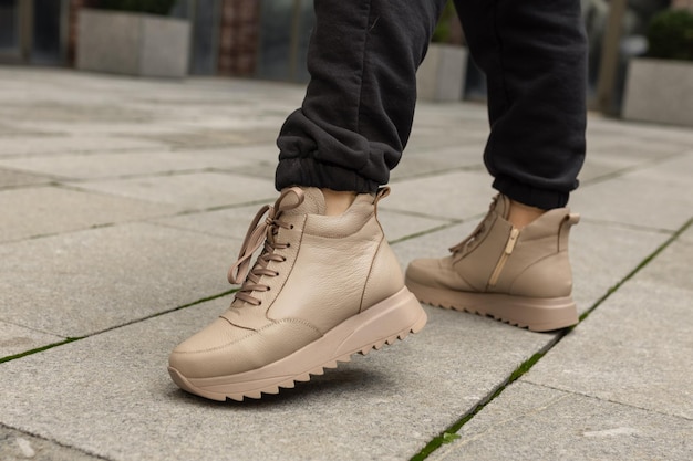 Ein Mann trägt ein Paar beige Stiefel, von denen einer eine Jeans trägt.