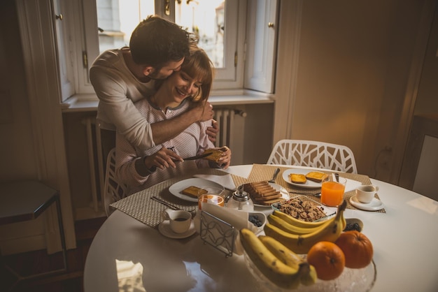 Foto ein mann umarmt eine frau, die zu hause frühstückt