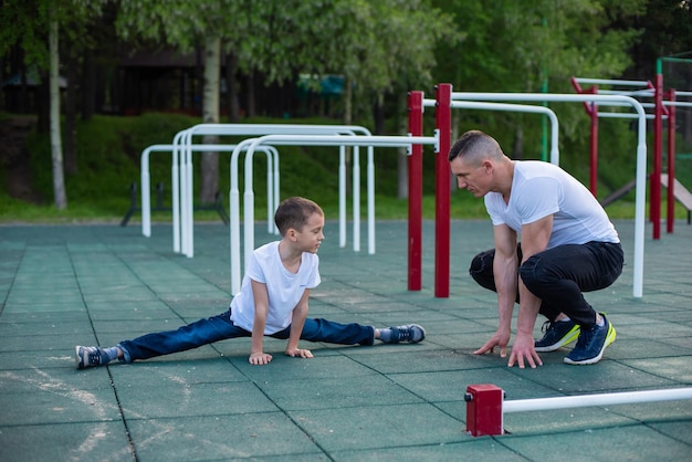 Ein Mann und ein Junge machen auf einem Spielplatz Dehnübungen.