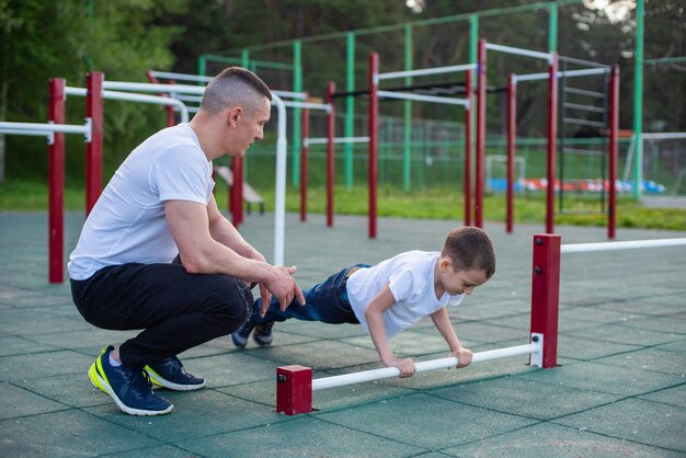 Ein Mann und ein Junge machen auf einem Spielplatz eine Langhantel.