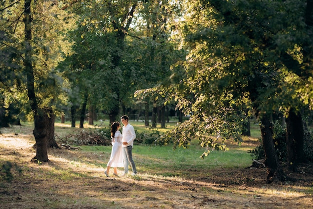 Ein Mann und ein Mädchen gehen zwischen hohen Bäumen die Wege eines Waldparks entlang
