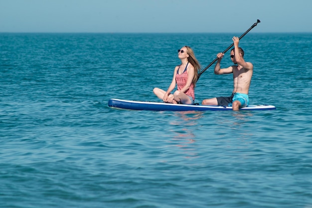 Ein Mann und ein Mädchen haben Spaß beim Schwimmen auf einem Sup-Board im Sommer im Meer