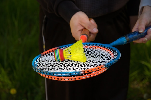 Ein Mann und ein Mädchen halten bunte Badmintonschläger. Auf den Schlägern befindet sich ein leuchtend bunter Flan.