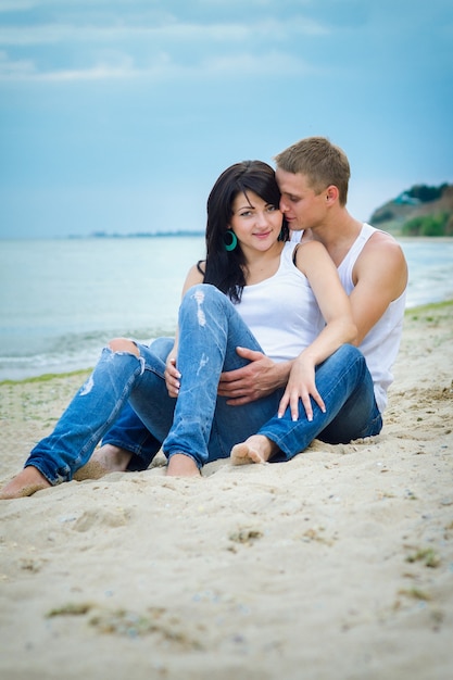 Ein Mann und ein Mädchen in Jeans und weißen T-Shirts am Meer