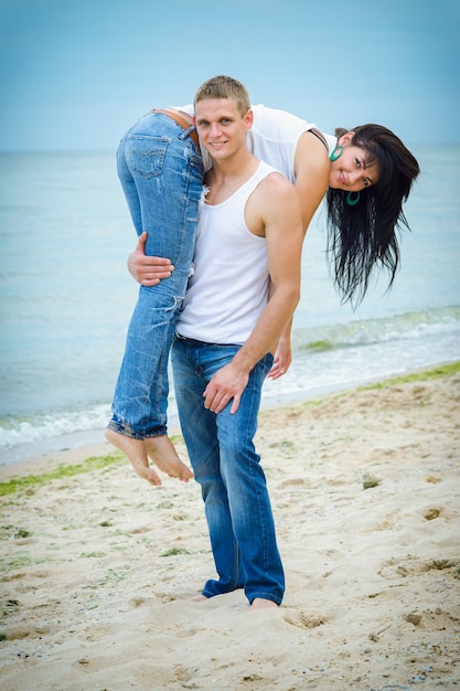 Ein Mann und ein Mädchen in Jeans und weißen T-Shirts am Meer