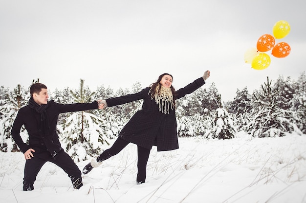 Ein Mann und ein Mädchen in warmen Kleidern und Schals bei einem Spaziergang im verschneiten Wald und auf dem Feld