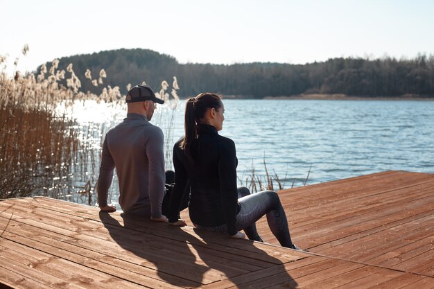 Ein Mann und ein Mädchen machen einen umgekehrten Liegestütz. Das Paar treibt Sport auf dem See. Fitness, Sport, Lifestyle