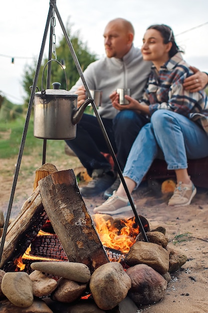 Foto ein mann und ein mädchen mit bechern in den händen wärmen sich am feuer.