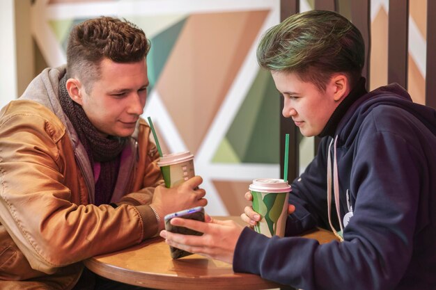 Ein Mann und ein Mädchen sitzen in einem Café und benutzen Smartphones. Kommunikation, Technik, Internet.