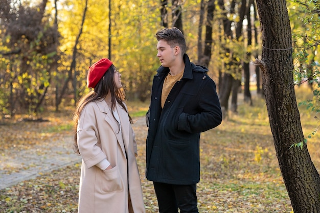 Ein Mann und ein Mädchen stehen in einem Herbstpark und unterhalten sich