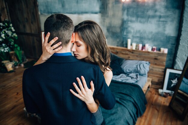 Ein Mann und ein Mädchen umarmen sich, stehen im Bett und am Fenster