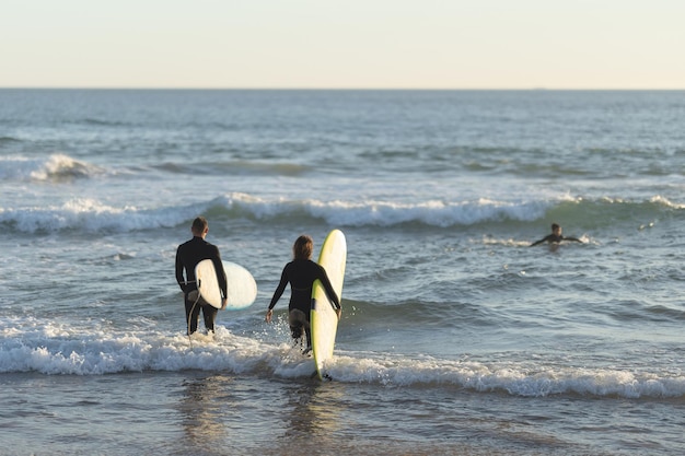 Ein Mann und eine Frau gehen mit Surfbrettern aufs Meer hinaus