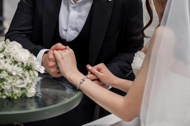 Ein Mann und eine Frau halten Händchen bei der Hochzeit von Jungvermählten