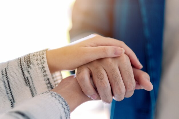 Ein Mann und eine Frau halten sich zum Trost und Mitgefühl die Hände