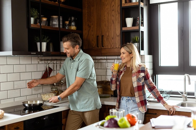 Foto ein mann und eine frau lachen, während sie in einer gemütlichen, gut organisierten küche kochen