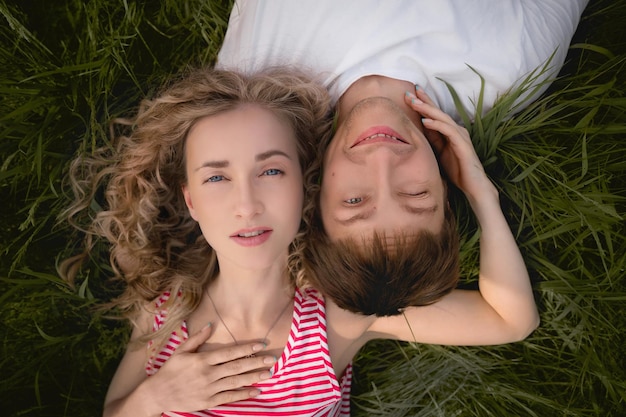 Ein Mann und eine Frau liegen Kopf an Kopf auf dem Gras und schauen in den Himmel