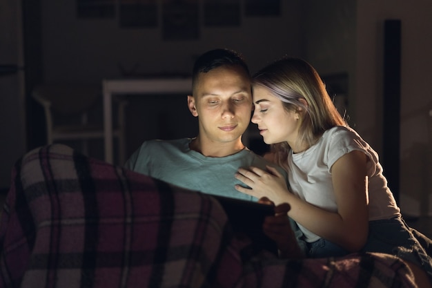 Ein Mann und eine Frau schauen sich abends zu Hause einen romantischen Film an