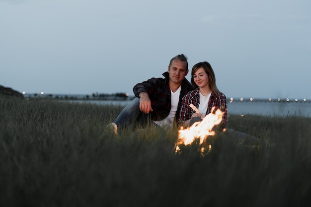 Ein Mann und eine Frau sitzen abends am Feuer