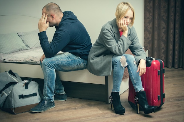 Ein mann und eine frau sitzen mit ihren koffern und ihrer tasche auf einem bett, das voneinander abgewandt ist das konzept der scheidungskrise bruchtrennung