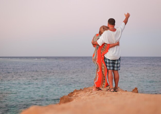 Ein Mann und eine Frau umarmen sich bei Sonnenuntergang am Strand