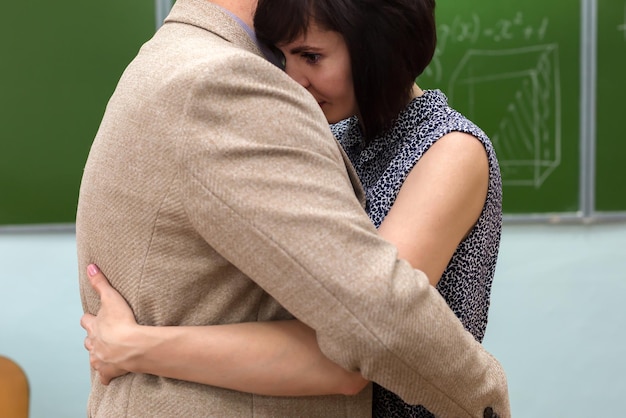 Ein Mann und eine Frau umarmen sich in einem Klassenzimmer an der Tafel