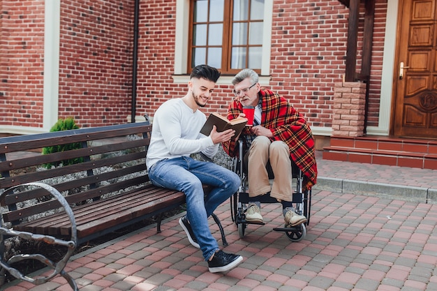 Ein Mann und sein Vater in der Nähe des Pflegeheims lesen ein Buch
