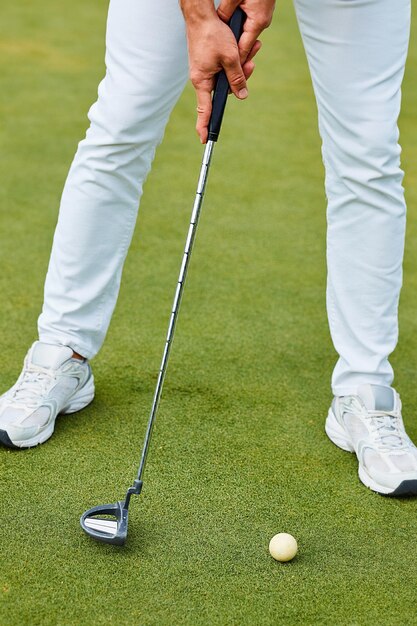 Ein Mann versucht, einen Golfball in ein Loch zu rollen. Sommergolfturnier. Die Szene strahlt mit dem Versprechen eines Triumphs auf den Grüns