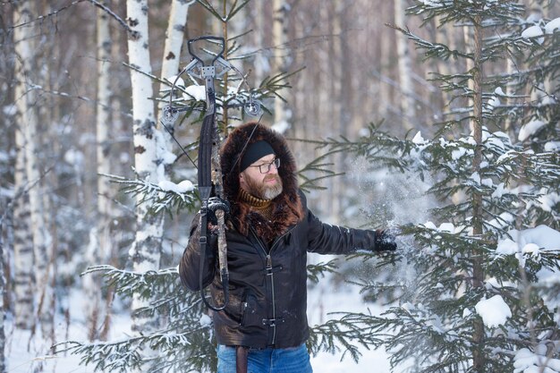 ein Mann von europäischem Aussehen schießt im Winterwald aus einer Sportarmbrust