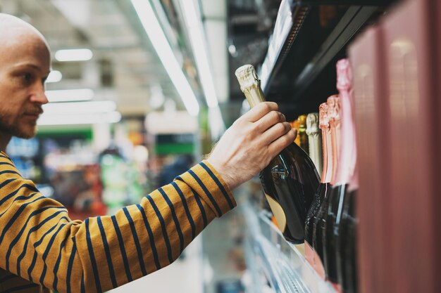 Foto ein mann wählt wein im supermarkt aus