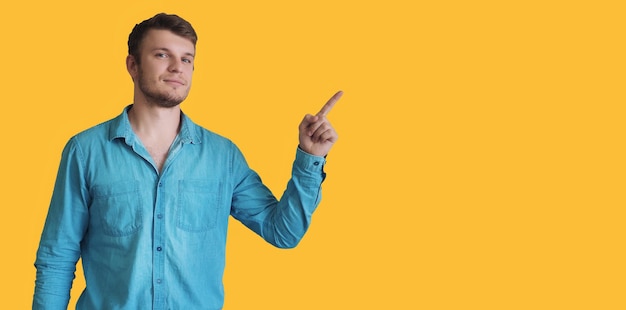 Ein Mann weist mit dem Finger auf das leere Leerraum auf dem gelben Hintergrund für das Einfügen von Informationen