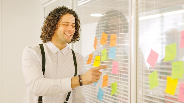 Ein Mann zeigt auf ein Postit und präsentiert Ideen in einem Meeting
