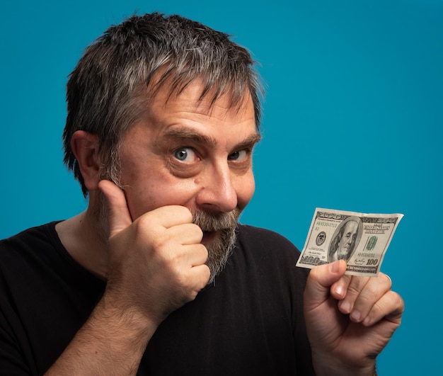 Ein Mann zeigt Aufregung, während er eine Hundert-Dollar-Note gegen einen blauen Hintergrund hält