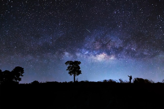 Ein Mann zeigte auf einen Meteor und eine Milchstraßengalaxie an einem Nachthimmel Langzeitbelichtungsfoto mit grainxA