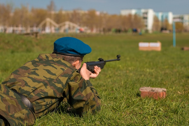 Ein Mann zielt auf ein Ziel. Scharfschütze liegt im Gras und schießt aus einem Maschinengewehr.