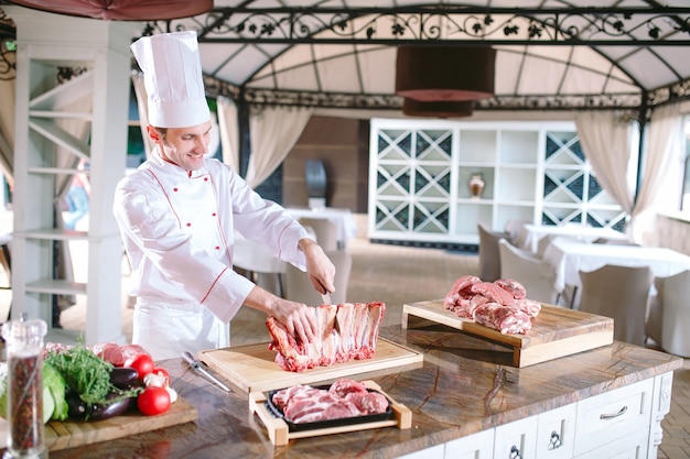 Ein Mannkoch schneidet Fleisch mit einem Messer in einem Restaurant.