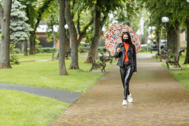 Ein maskiertes Mädchen geht die Straße entlang. Ein Mädchen in einer Schutzmaske geht mit einem in den Park