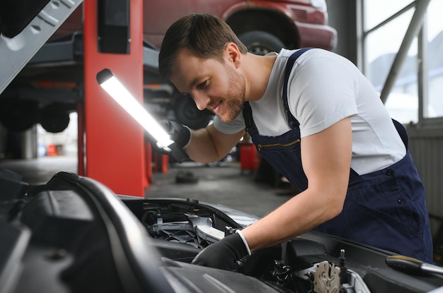 Foto ein mechaniker führt in der werkstatt des mechanikers eine autoprüfung unter der motorhaube mit taschenlampe durch