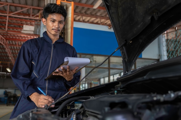 Ein Mechaniker-Service-Auto in der Garage ist Papiercheck eine Liste Autos.