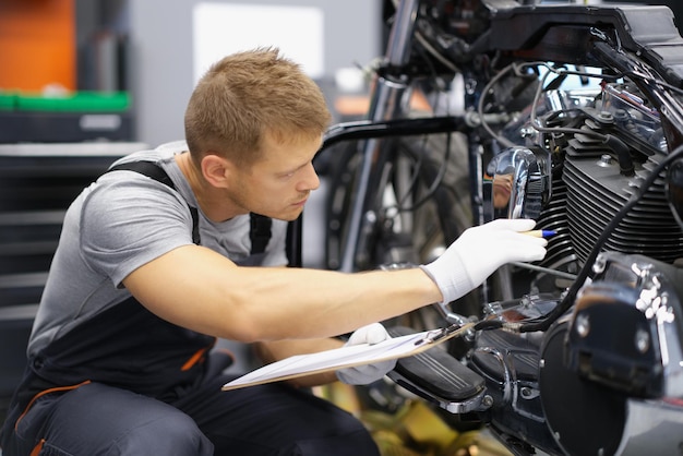 Ein Mechaniker sitzt in einer Werkstatt neben einem Motorrad